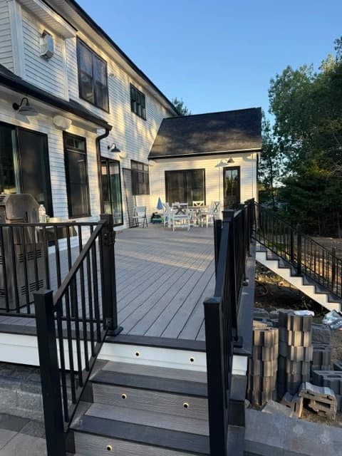 Composite deck walkway with black aluminum railing overlooking a wooded backyard